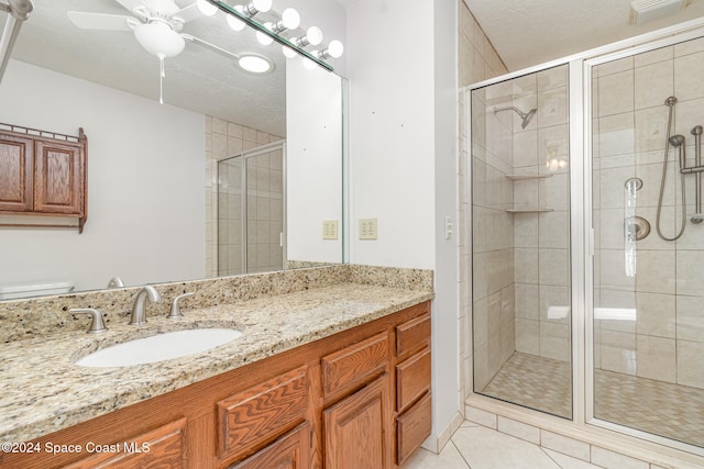 bathroom with tile patterned floors, an enclosed shower, a textured ceiling, vanity, and ceiling fan