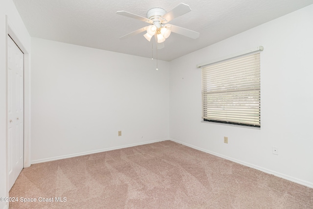 unfurnished bedroom featuring light carpet, a closet, and ceiling fan