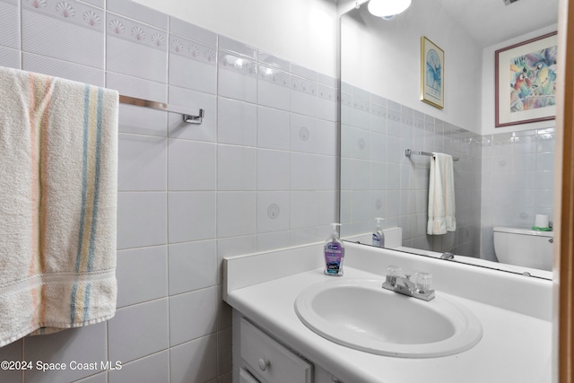 bathroom with vanity, toilet, and tile walls