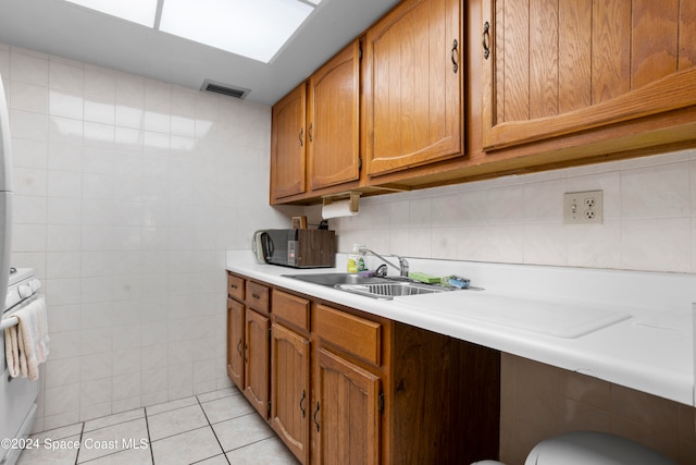 kitchen featuring sink, light tile patterned floors, tile walls, and range