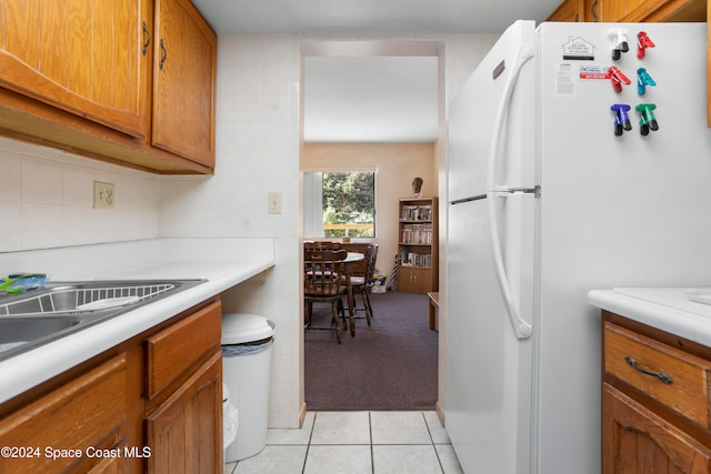 kitchen with light tile patterned floors, white refrigerator, and backsplash