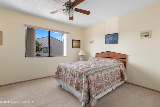 carpeted bedroom with ceiling fan and a textured ceiling