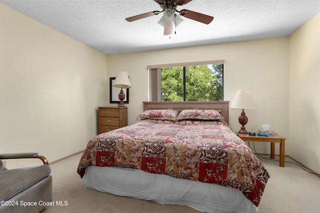 bedroom featuring ceiling fan, light colored carpet, and a textured ceiling