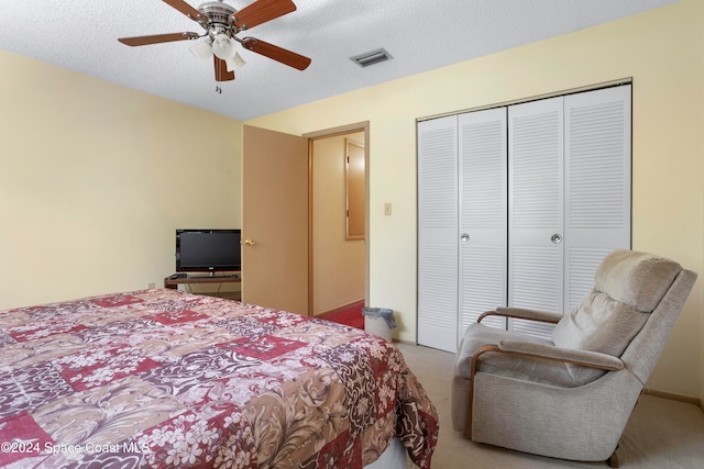 carpeted bedroom with a closet, ceiling fan, and a textured ceiling