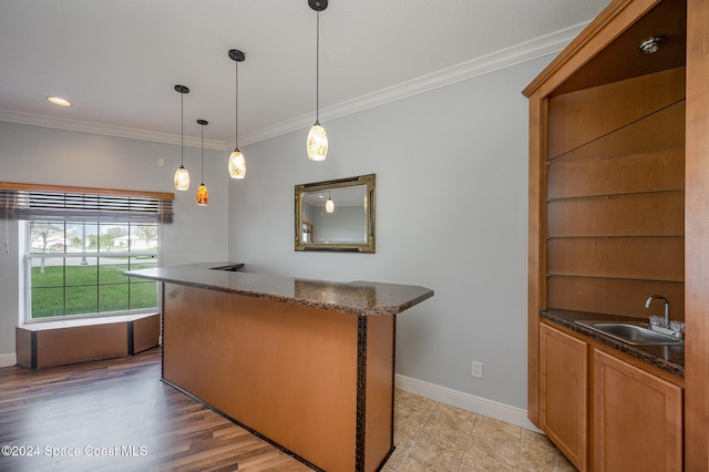 kitchen featuring pendant lighting, light hardwood / wood-style flooring, crown molding, and sink