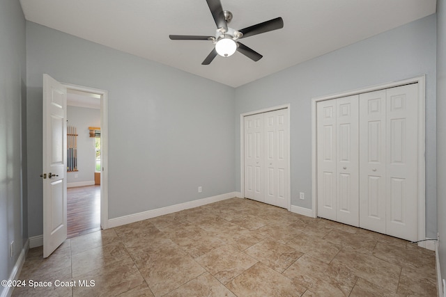 unfurnished bedroom featuring ceiling fan and multiple closets