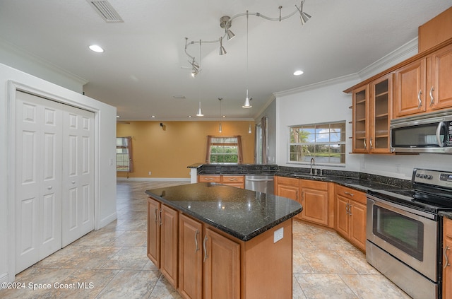 kitchen with sink, crown molding, dark stone counters, a kitchen island, and appliances with stainless steel finishes