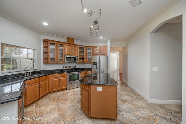 kitchen with a center island, sink, stainless steel appliances, crown molding, and dark stone counters