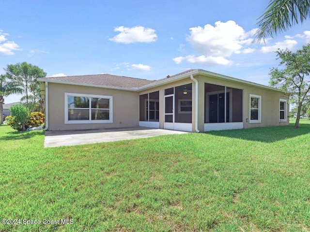 back of property with a sunroom, a patio area, and a lawn