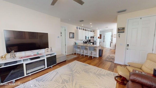 living room with light wood-type flooring and ceiling fan