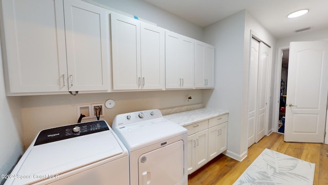 laundry room with cabinets, light hardwood / wood-style floors, and washing machine and clothes dryer