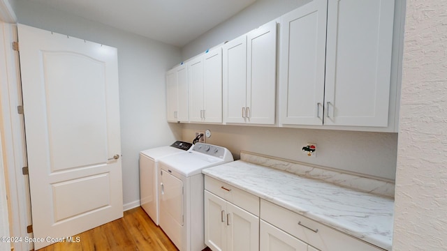 washroom featuring separate washer and dryer, cabinets, and light hardwood / wood-style floors