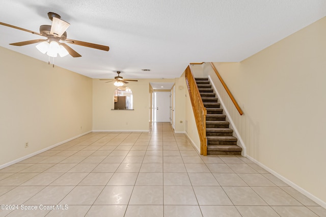 unfurnished living room with a textured ceiling, ceiling fan, and light tile patterned flooring