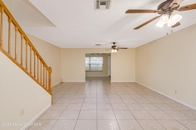 spare room featuring ceiling fan, light tile patterned flooring, and a textured ceiling