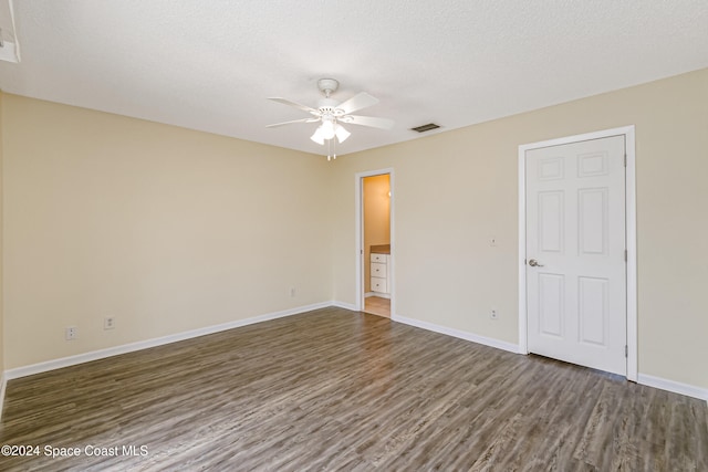 unfurnished room with a textured ceiling, ceiling fan, and dark wood-type flooring