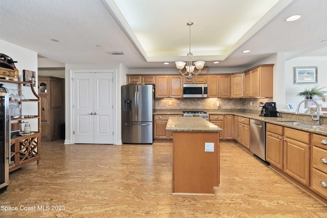 kitchen with a center island, sink, stainless steel appliances, light stone counters, and backsplash