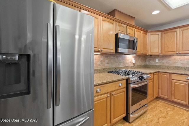 kitchen with tasteful backsplash, a skylight, light stone counters, and stainless steel appliances