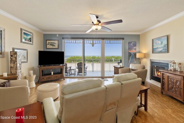 living room featuring ceiling fan, ornamental molding, a textured ceiling, and light hardwood / wood-style flooring