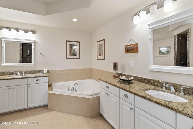 bathroom with tile patterned flooring, vanity, and a relaxing tiled tub