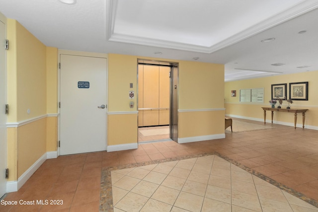 unfurnished room featuring a raised ceiling, elevator, and light tile patterned floors