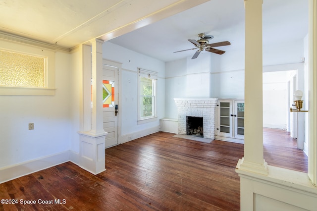 unfurnished living room with a fireplace, dark hardwood / wood-style flooring, decorative columns, and ceiling fan