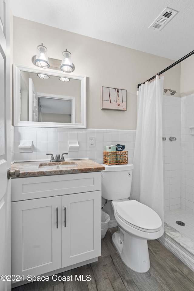 bathroom with a shower with curtain, backsplash, wood-type flooring, a textured ceiling, and vanity