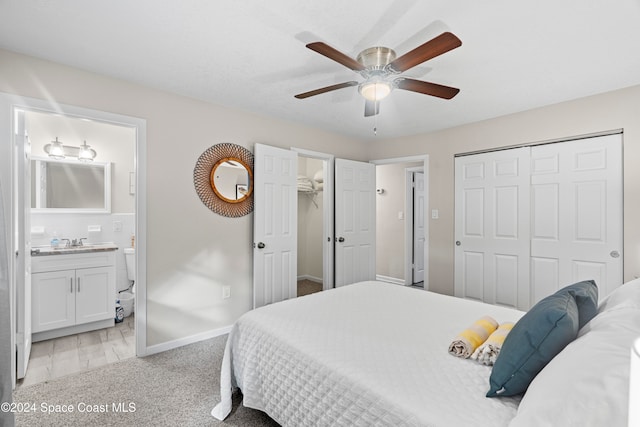 carpeted bedroom featuring ensuite bath, ceiling fan, and sink