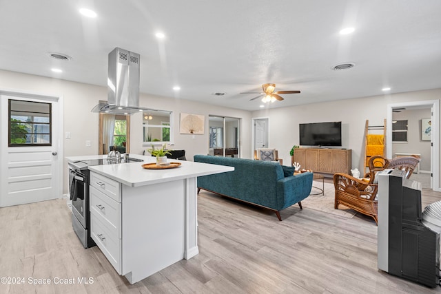 kitchen featuring island exhaust hood, light wood-type flooring, a center island with sink, white cabinetry, and stainless steel range with electric cooktop