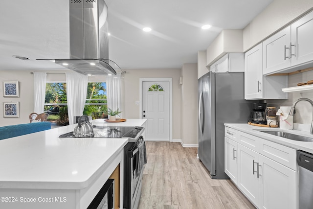 kitchen with white cabinets, sink, light wood-type flooring, appliances with stainless steel finishes, and a kitchen island