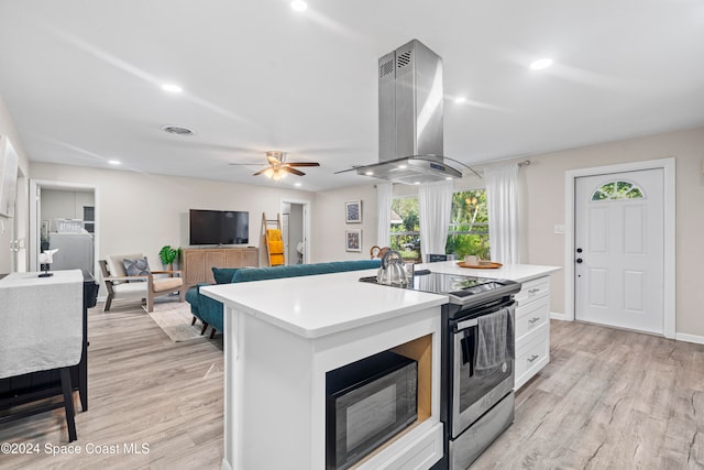 kitchen with stainless steel range with electric stovetop, island range hood, a kitchen island with sink, light hardwood / wood-style flooring, and white cabinetry