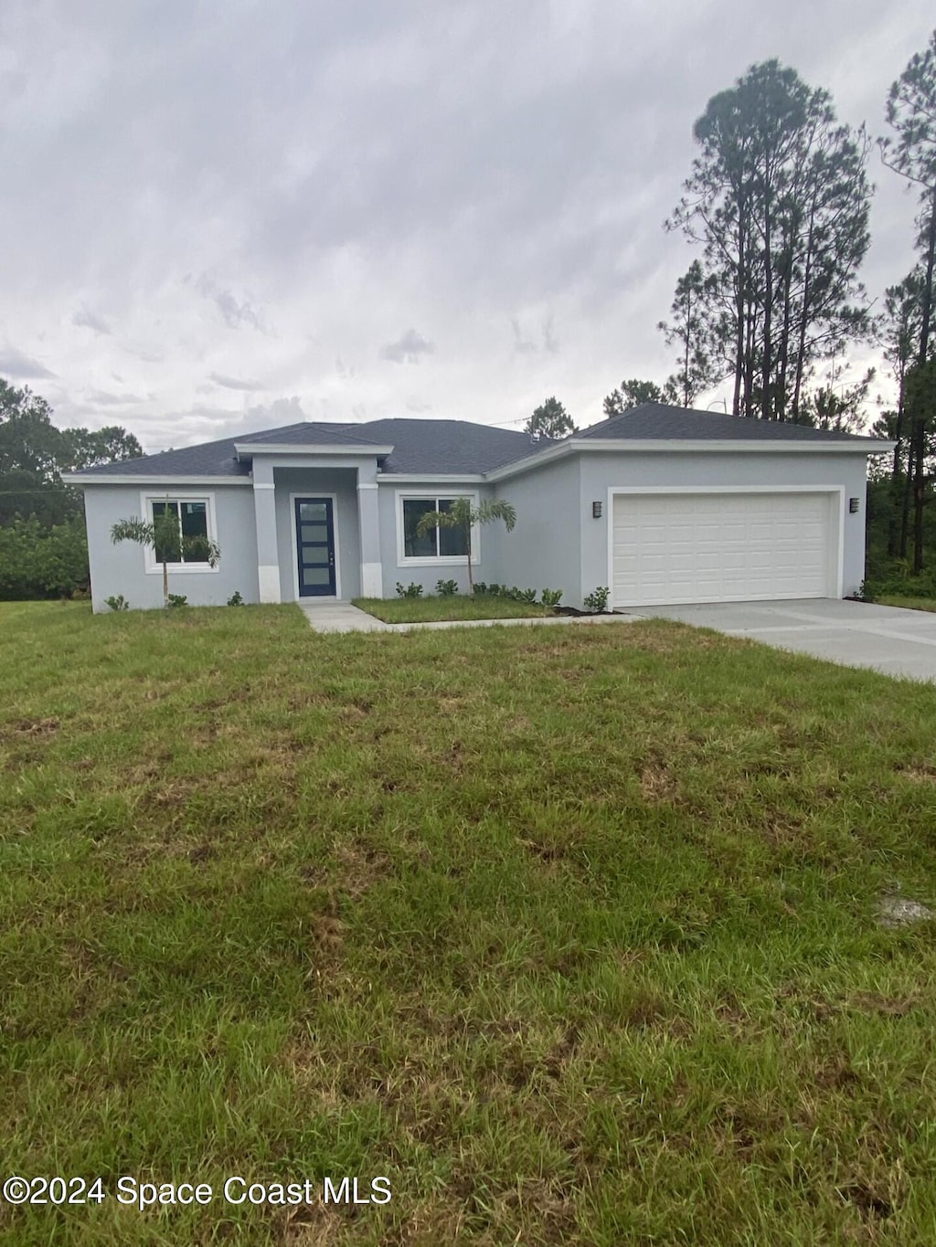 ranch-style house featuring a garage and a front lawn