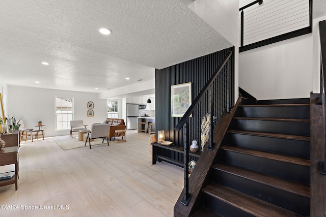 staircase with a textured ceiling and hardwood / wood-style flooring