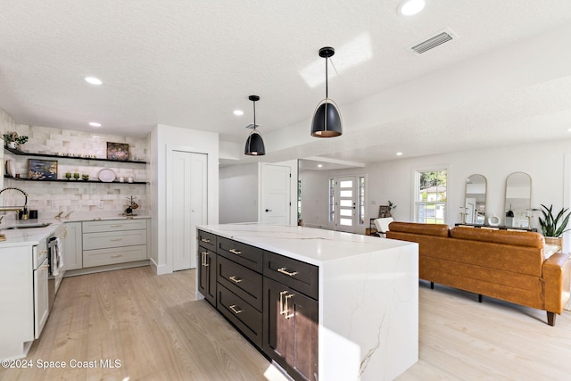 kitchen with white cabinets, light stone countertops, light hardwood / wood-style flooring, and hanging light fixtures