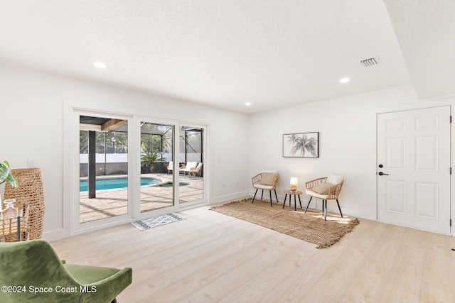 living area with a textured ceiling and light wood-type flooring