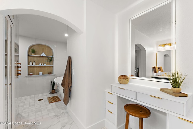 bathroom featuring tiled shower and vanity