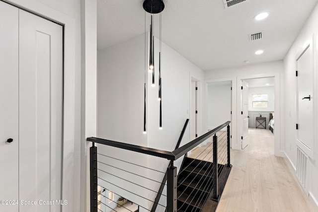 corridor featuring light hardwood / wood-style floors and a textured ceiling