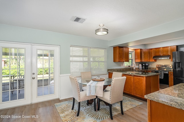 kitchen with french doors, black fridge, a wealth of natural light, stainless steel range with electric stovetop, and light hardwood / wood-style flooring