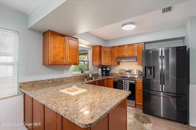 kitchen with sink, kitchen peninsula, stainless steel appliances, and light wood-type flooring