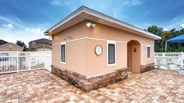 exterior space featuring stone siding, fence, a patio, and stucco siding