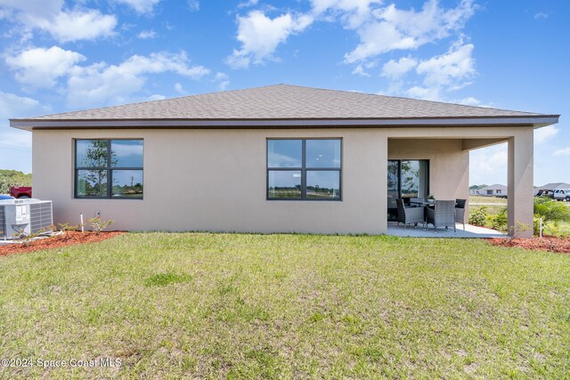 rear view of house with a yard, central AC unit, a patio area, and stucco siding