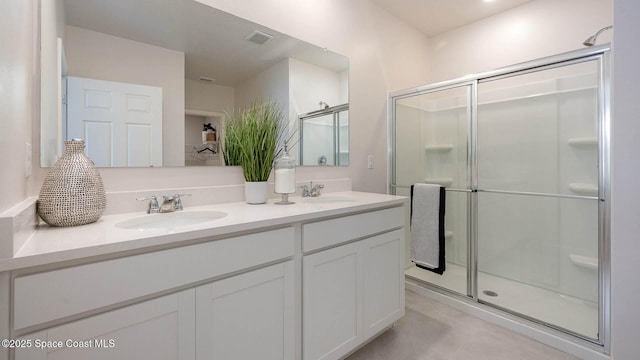 full bath featuring a stall shower, visible vents, a sink, and double vanity