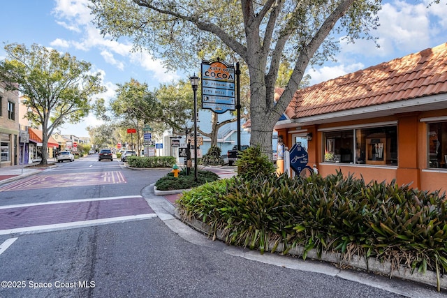 view of road featuring sidewalks, traffic signs, curbs, and street lights