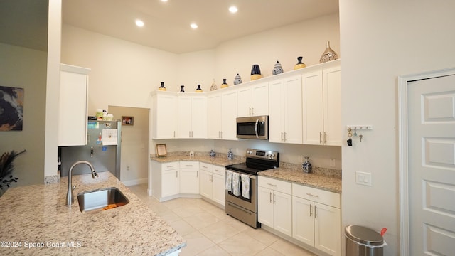 kitchen with light stone countertops, stainless steel appliances, and white cabinets