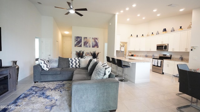 tiled living room featuring a high ceiling, ceiling fan, and sink