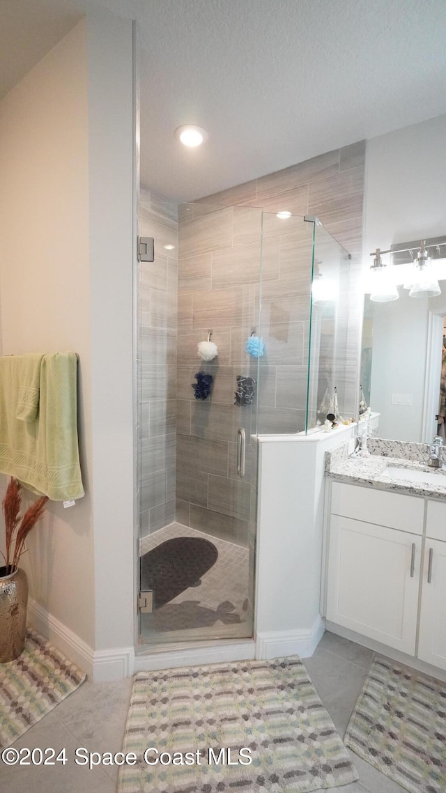 bathroom featuring a textured ceiling, vanity, tile patterned floors, and walk in shower