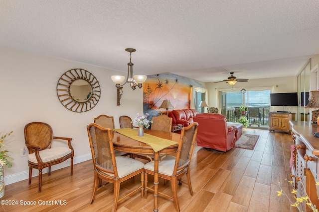 dining room with a textured ceiling, ceiling fan with notable chandelier, and light hardwood / wood-style floors