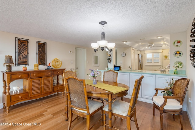 dining room featuring an inviting chandelier, light wood-style flooring, visible vents, and a textured ceiling