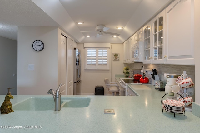 kitchen with sink, stove, white cabinetry, and stainless steel refrigerator with ice dispenser