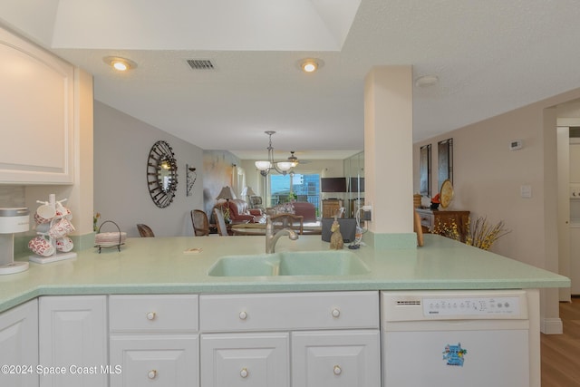 kitchen featuring white cabinetry, sink, an inviting chandelier, white dishwasher, and hardwood / wood-style flooring