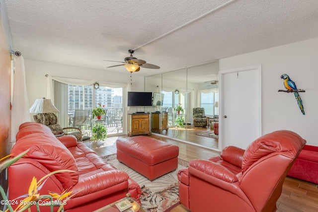 living area with ceiling fan, a textured ceiling, and wood finished floors